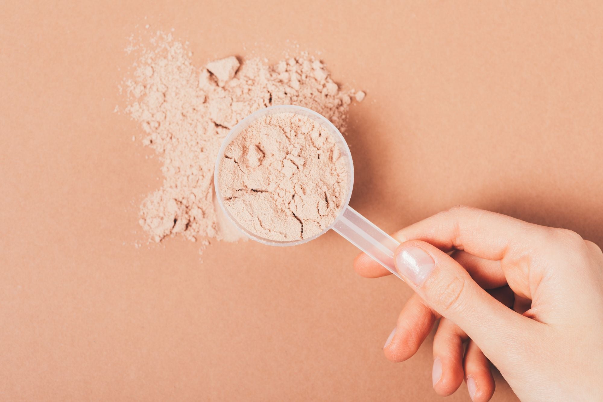 A woman holding a scoop of pre-workout, while wondering if pre-workout causes acne.